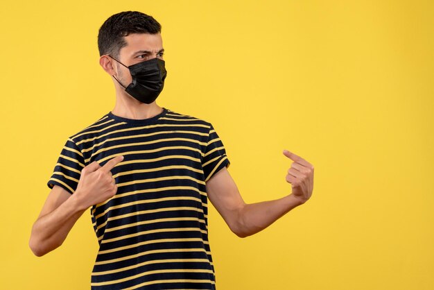 Vorderansicht junger Mann im schwarz-weiß gestreiften T-Shirt, das auf sich selbst gelben Hintergrund zeigt