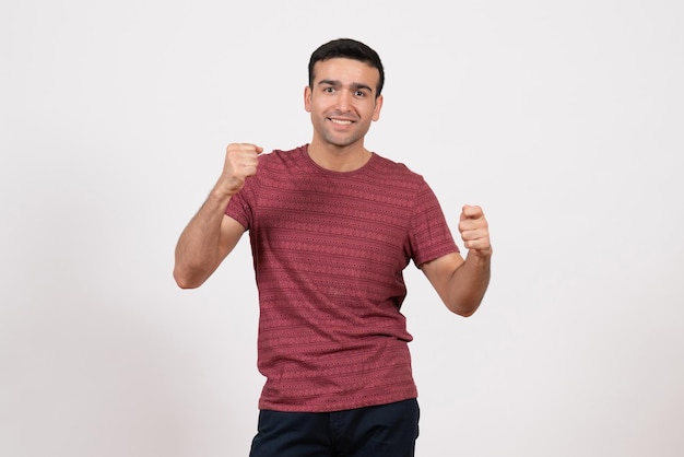 Vorderansicht junger Mann im T-Shirt posiert und freut sich auf weißem Hintergrund