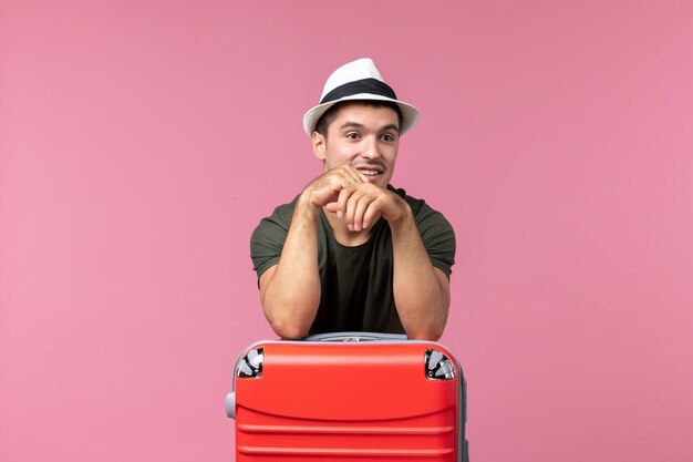 Vorderansicht junger Mann im Urlaub mit seiner roten Tasche auf dem rosa Raum