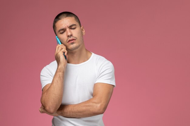 Vorderansicht junger Mann im weißen Hemd, das am Telefon auf rosa Hintergrund spricht