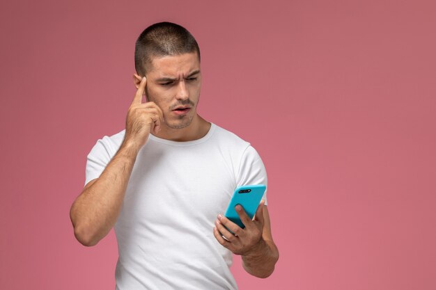 Vorderansicht junger Mann im weißen Hemd unter Verwendung seines Telefons auf rosa Hintergrund