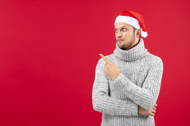 Vorderansicht junger Mann in warmem Trikot auf rotem Tisch Neujahr Weihnachtsferien Farbe Emotion