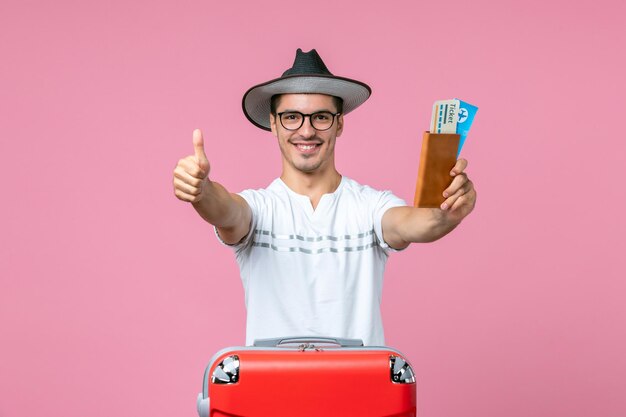 Vorderansicht junger Mann lächelt und hält Flugtickets auf rosa Wand Reise Reise Flugzeug männlich Foto Farbe Urlaub