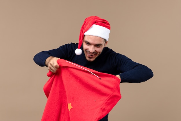 Vorderansicht junger mann mit aufgeregtem ausdruck auf braunem boden weihnachtsfeiertag santa