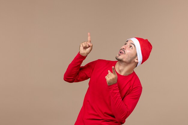 Vorderansicht junger Mann mit aufgeregtem Ausdruck auf einem Weihnachtsfeiertag der braunen Hintergrundemotion