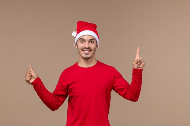 Vorderansicht junger Mann mit aufgeregtem Gesicht auf braunem Hintergrundweihnachtsemotionsfeiertagsmann