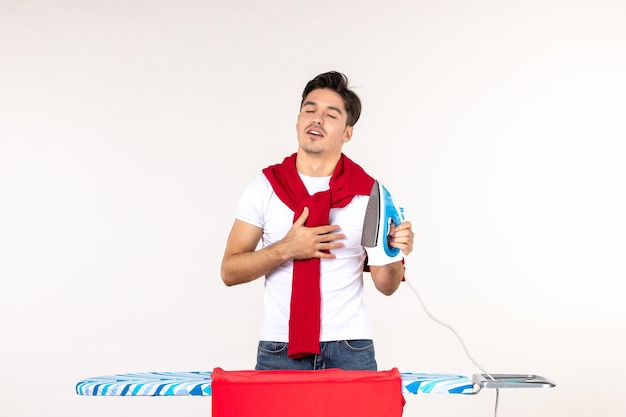 Vorderansicht junger Mann mit Bügeleisen auf weißem Hintergrund Wäsche Hausarbeit Arbeit Mann Relief Emotion nach Hause sauber