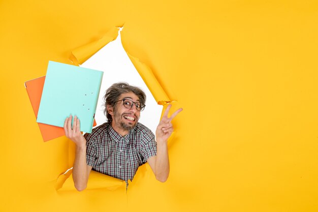 Vorderansicht junger Mann mit Dateien auf gelbem Hintergrund Farbe Büro Urlaub Job Weihnachten Arbeit Emotion