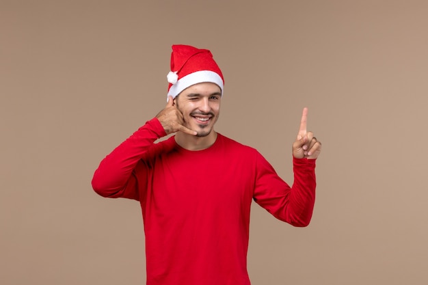 Kostenloses Foto vorderansicht junger mann mit dem zwinkernden ausdruck auf braunem hintergrundweihnachtsemotionsfeiertagsmann