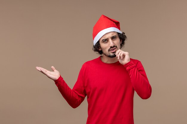 Vorderansicht junger Mann mit denkendem Ausdruck auf einem braunen Hintergrundfeiertagsemotionsweihnachten