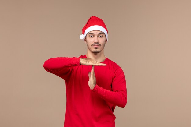 Vorderansicht junger Mann mit denkendem Ausdruck auf einem Weihnachtsfeiertag der braunen Hintergrundemotion