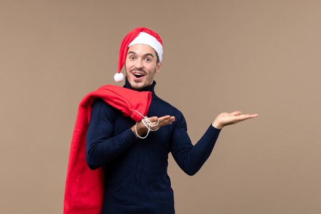 Vorderansicht junger Mann mit Geschenktüte auf braunem Schreibtisch Emotion Urlaub Weihnachten