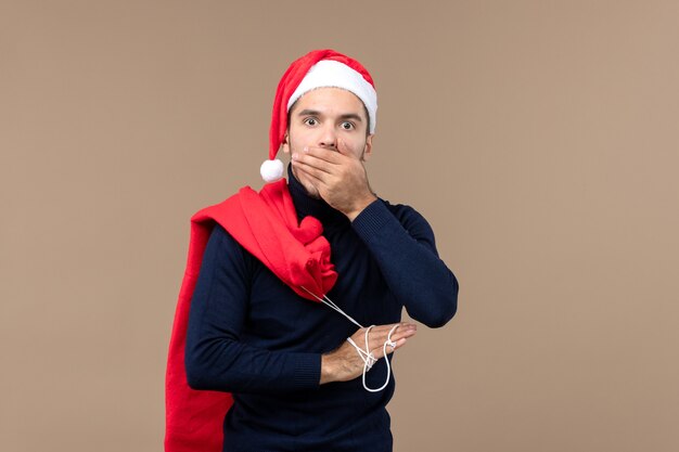 Vorderansicht junger Mann mit Geschenktüte auf braunem Schreibtisch Weihnachtsfeiertag Santa