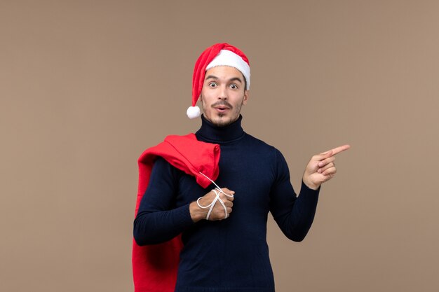 Vorderansicht junger Mann mit Geschenktüte, Feiertagsgefühle Weihnachten
