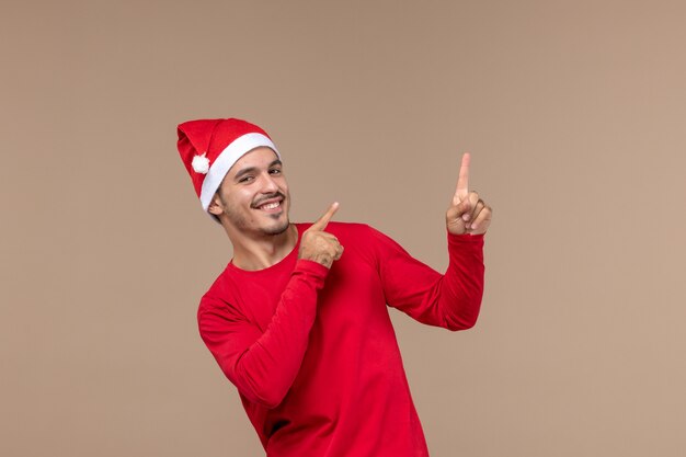 Vorderansicht junger Mann mit lächelndem Ausdruck auf braunem Hintergrundweihnachtsemotionsfeiertagsmann