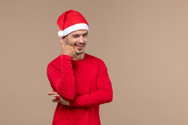 Vorderansicht junger Mann mit lächelndem Ausdruck auf Weihnachtsfeiertagsemotion des braunen Hintergrunds