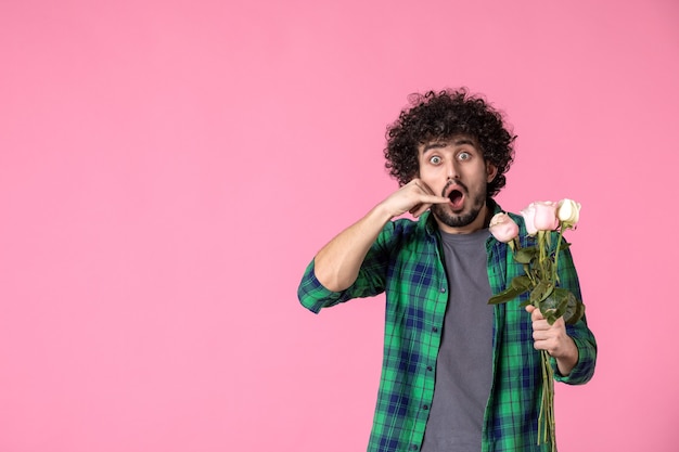 Vorderansicht junger Mann mit rosa Rosen auf Pinkr