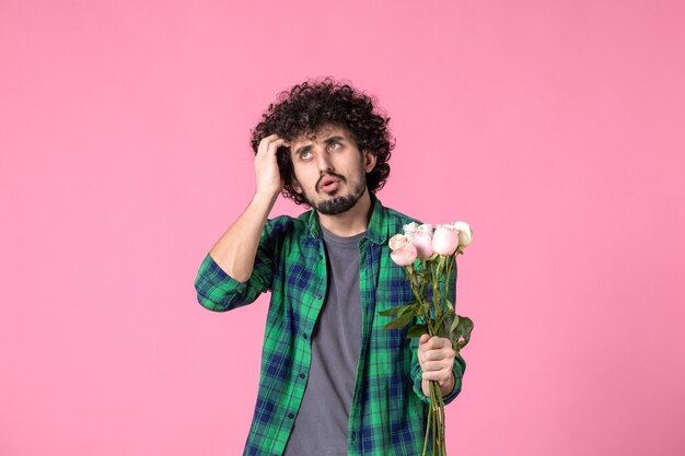 Vorderansicht junger Mann mit rosa Rosen auf rosa Farbe