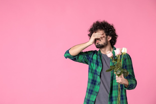 Vorderansicht junger Mann mit rosa Rosen auf rosa