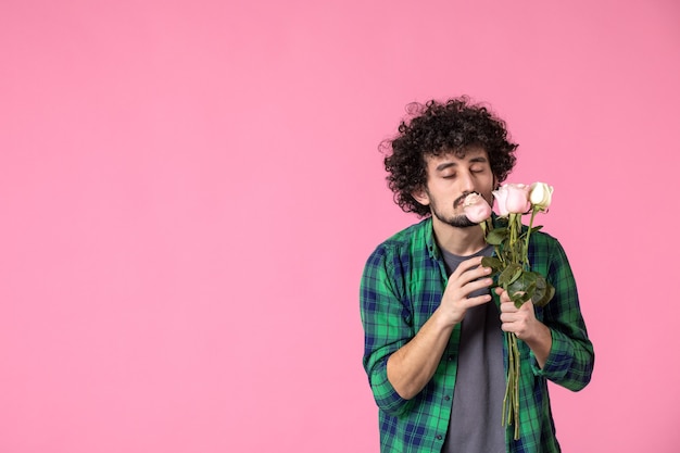 Vorderansicht junger mann mit rosa rosen auf rosa