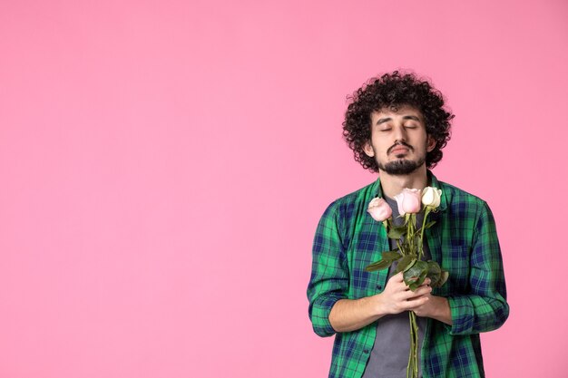 Vorderansicht junger Mann mit rosa Rosen auf rosa