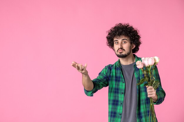 Vorderansicht junger Mann mit rosa Rosen auf Rosa