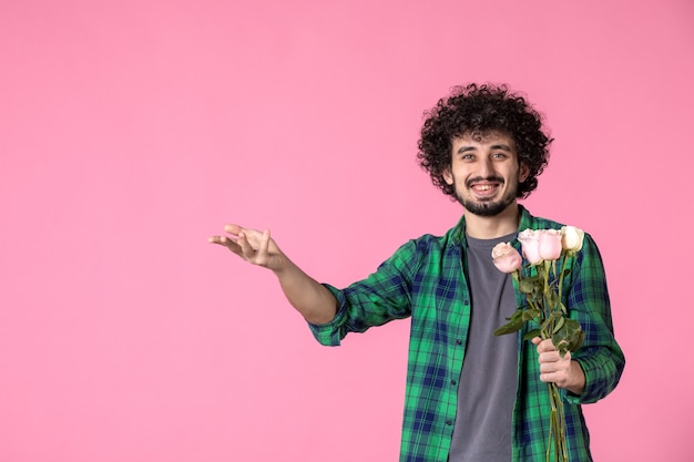 Vorderansicht junger Mann mit rosa Rosen auf rosa