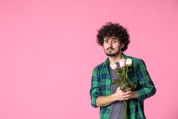 Vorderansicht junger Mann mit rosa Rosen auf rosa