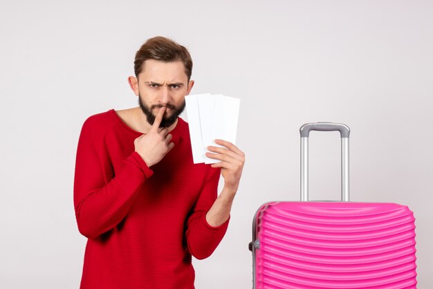 Vorderansicht junger Mann mit rosa Tasche und Haltekarten auf weißem Wandreiseflugfarbtour-Touristenurlaubsfoto