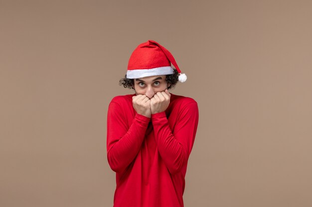 Vorderansicht junger Mann mit rotem Weihnachtsumhang auf Weihnachtsfeindlichkeitsfeiertag des braunen Bodens