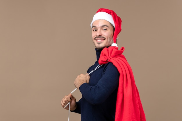 Vorderansicht junger Mann mit roter Geschenktüte, Weihnachtsfeiertagsgefühl