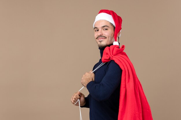 Vorderansicht junger Mann mit roter Geschenktüte, Weihnachtsfeiertagsgefühl