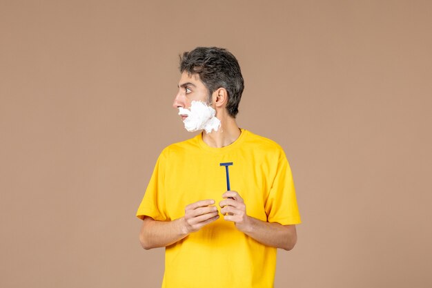 Vorderansicht junger Mann mit Schaum auf seinem Gesicht, das vorbereitet, sich auf rosa Hintergrund zu rasieren