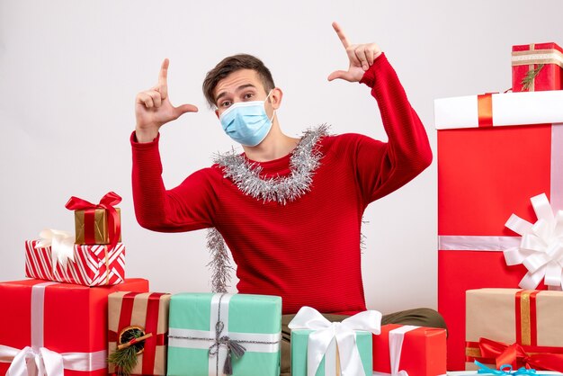 Vorderansicht junger Mann mit sitzenden Weihnachtsgeschenken auf weißem Hintergrund