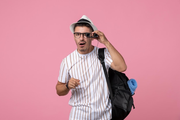 Vorderansicht junger Mann mit Tasche und Fernglas auf dem rosa Hintergrund