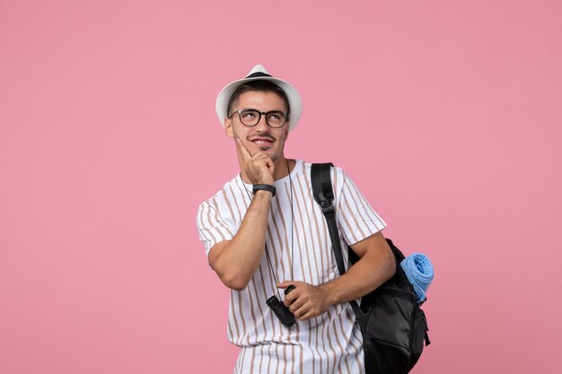 Vorderansicht junger Mann mit Tasche und Fernglas auf dem rosa Hintergrund