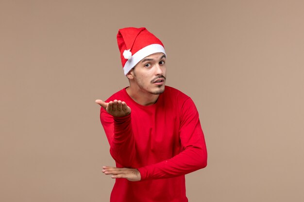 Vorderansicht junger Mann mit verwirrtem Gesicht auf braunem Hintergrundweihnachtsemotionsfeiertagsmann