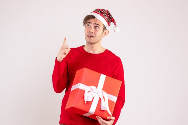 Vorderansicht junger Mann mit Weihnachtsmütze, die hoch stehend auf weißem Hintergrund betrachtet