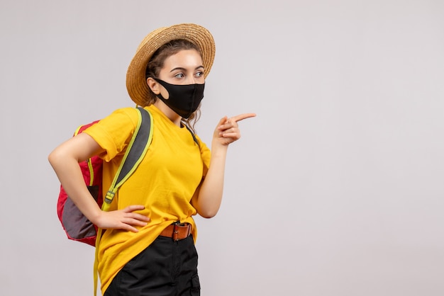 Vorderansicht junger Reisender mit Rucksack nach rechts zeigend