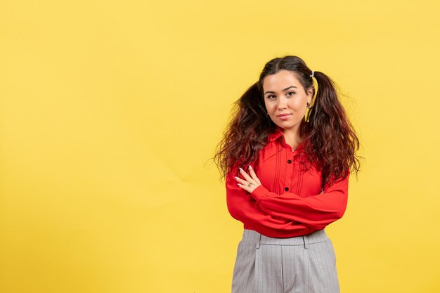 Vorderansicht junges Mädchen in roter Bluse mit süßem Haar, das nur auf gelbem Hintergrund steht Kinderfarbe Kind Mädchen Jugend Unschuld