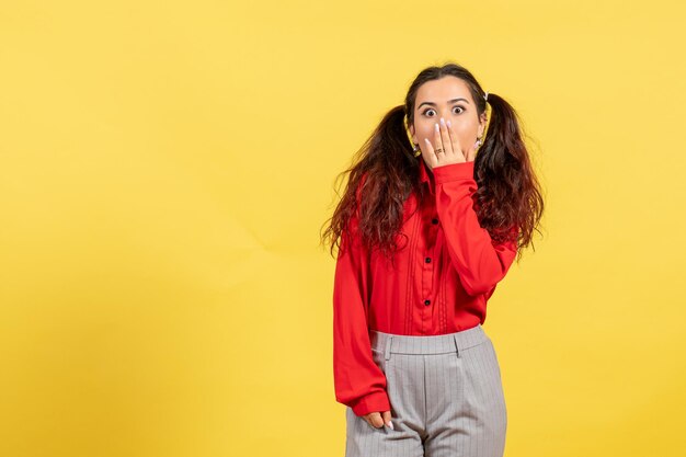 Vorderansicht junges Mädchen in roter Bluse mit überraschtem Gesicht auf gelbem Hintergrund Farbe Unschuld Kind Mädchen Jugend Kind