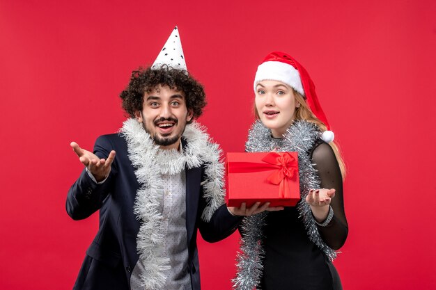 Vorderansicht junges Paar mit Geschenk feiern auf rotem Boden Party Weihnachtsliebe