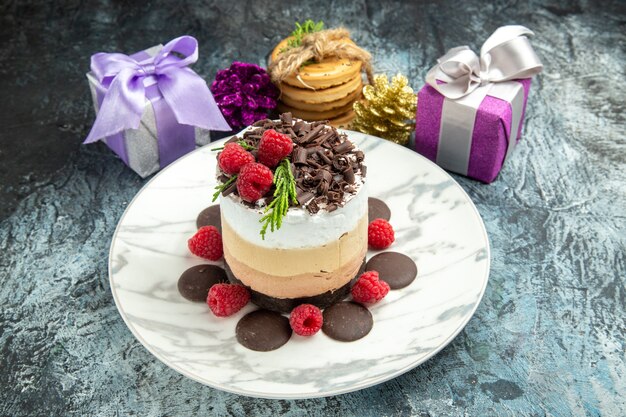 Vorderansicht-Käsekuchen mit Schokolade auf ovalem Teller gebundene Plätzchen-Weihnachtsverzierungen auf grauem Hintergrund