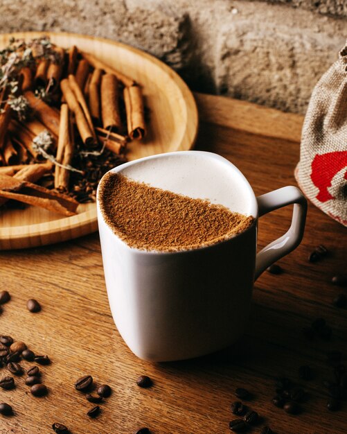 Vorderansicht Kaffee zusammen mit Zimt und Kaffeesamen auf dem braunen Boden