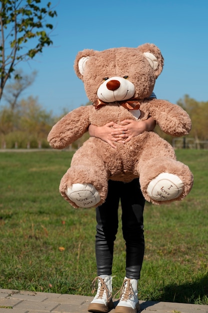 Kostenloses Foto vorderansicht kind hält teddybär im freien