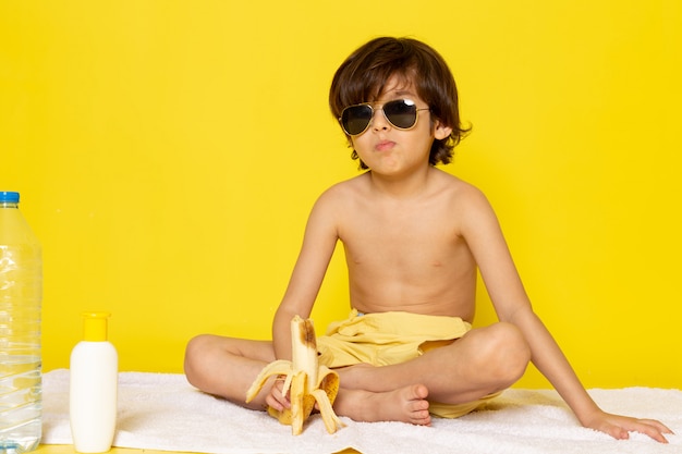 Vorderansicht Kind Junge in Sonnenbrille auf dem gelben Schreibtisch