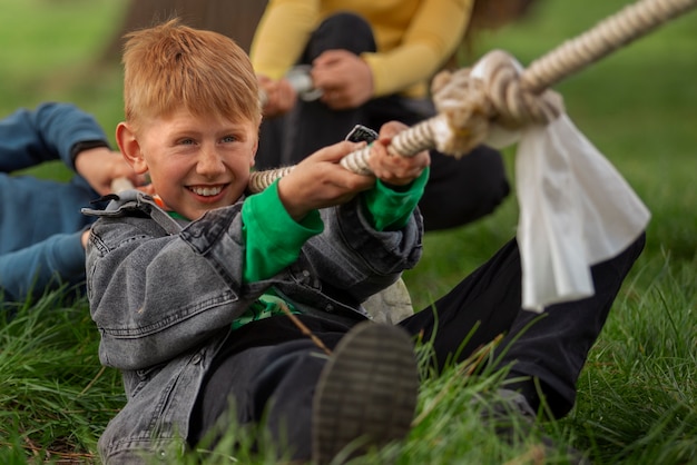 Vorderansicht: Kinder spielen Tauziehen im Park