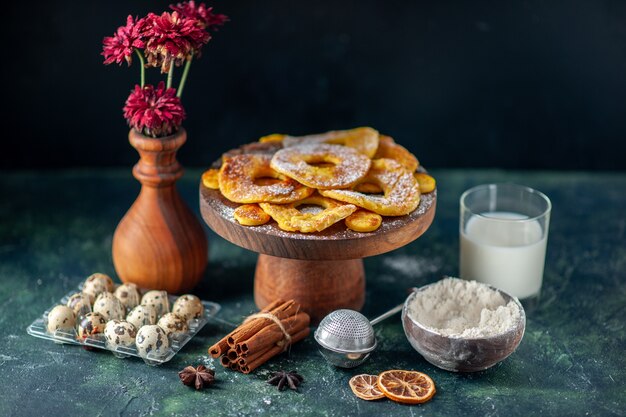 Vorderansicht kleine leckere Kuchen in Ananasringform mit Milch auf der dunklen Oberfläche