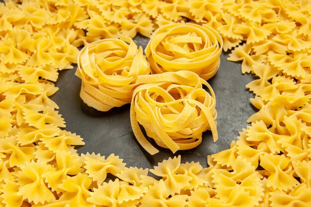 Vorderansicht kleine rohe Nudeln auf dunklem Foto viele Teig italienische Pasta Farbe Essen Mahlzeit