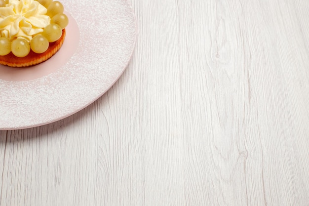 Vorderansicht kleine Sahnetorte mit Trauben auf weißem Bodentorte Obstkuchen Dessertkeksplätzchen